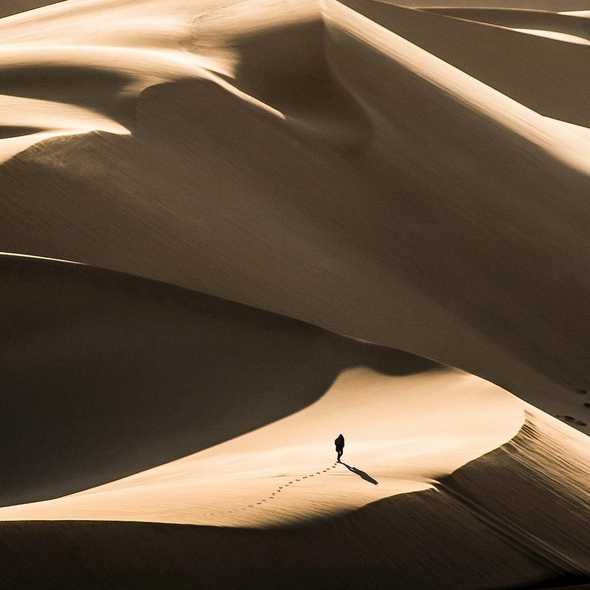 Photo of a man walking through the desert by Dan Grinwis