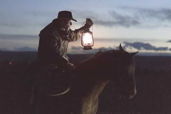 Man riding a horse, lighting his path with a lanterm by Priscilla De Preez