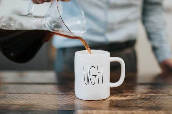 Pouring coffee into a mug marked "UGH". Photo by Nathan Dumlao